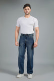 Man wearing a white t-shirt and blue jeans against a gray background