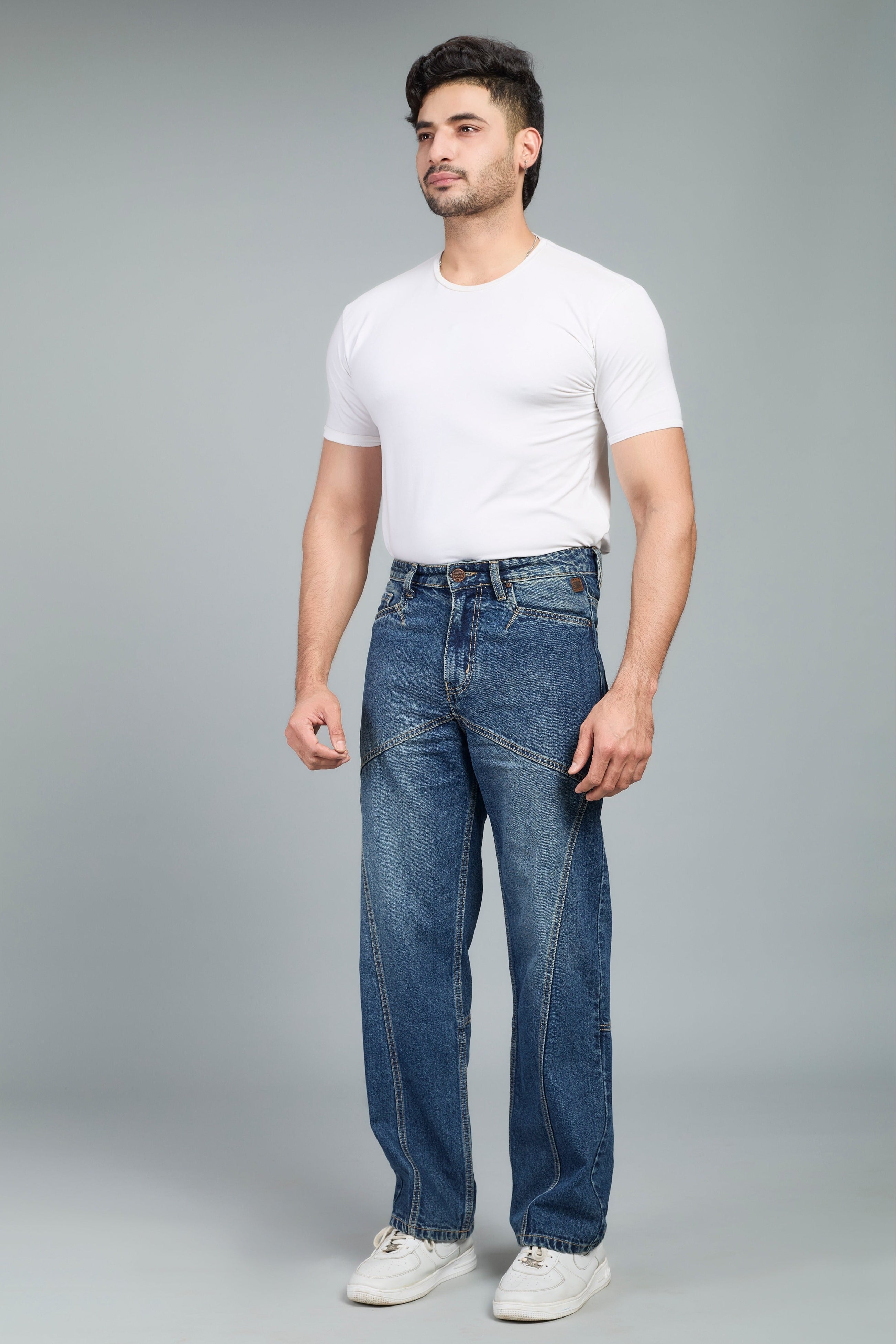 Man wearing a white t-shirt and blue jeans on a gray background