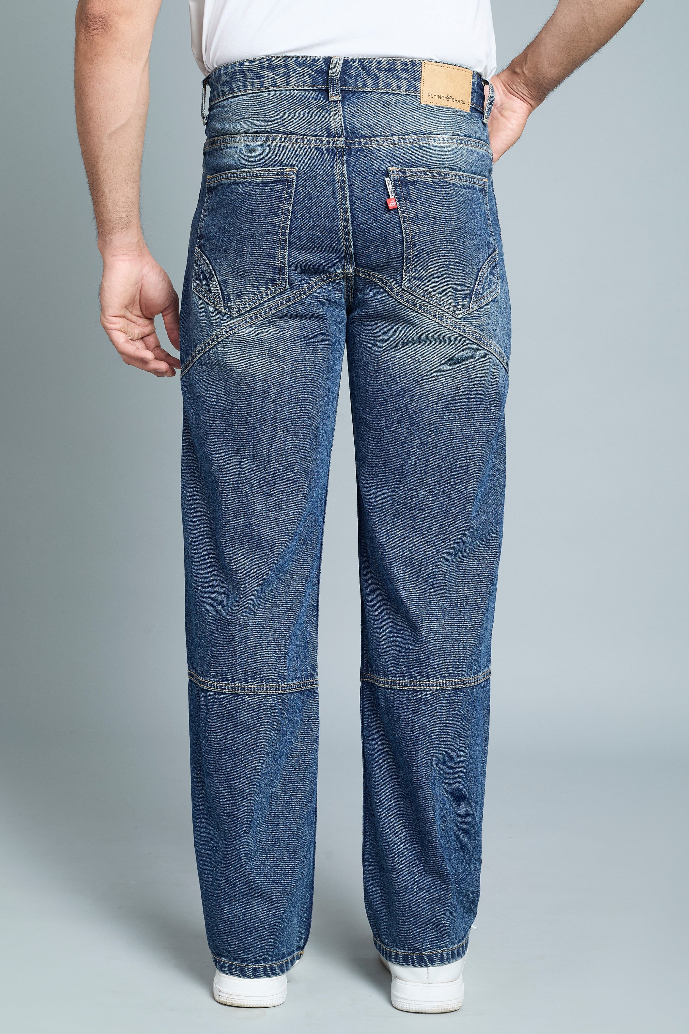 Person wearing blue jeans on a gray background