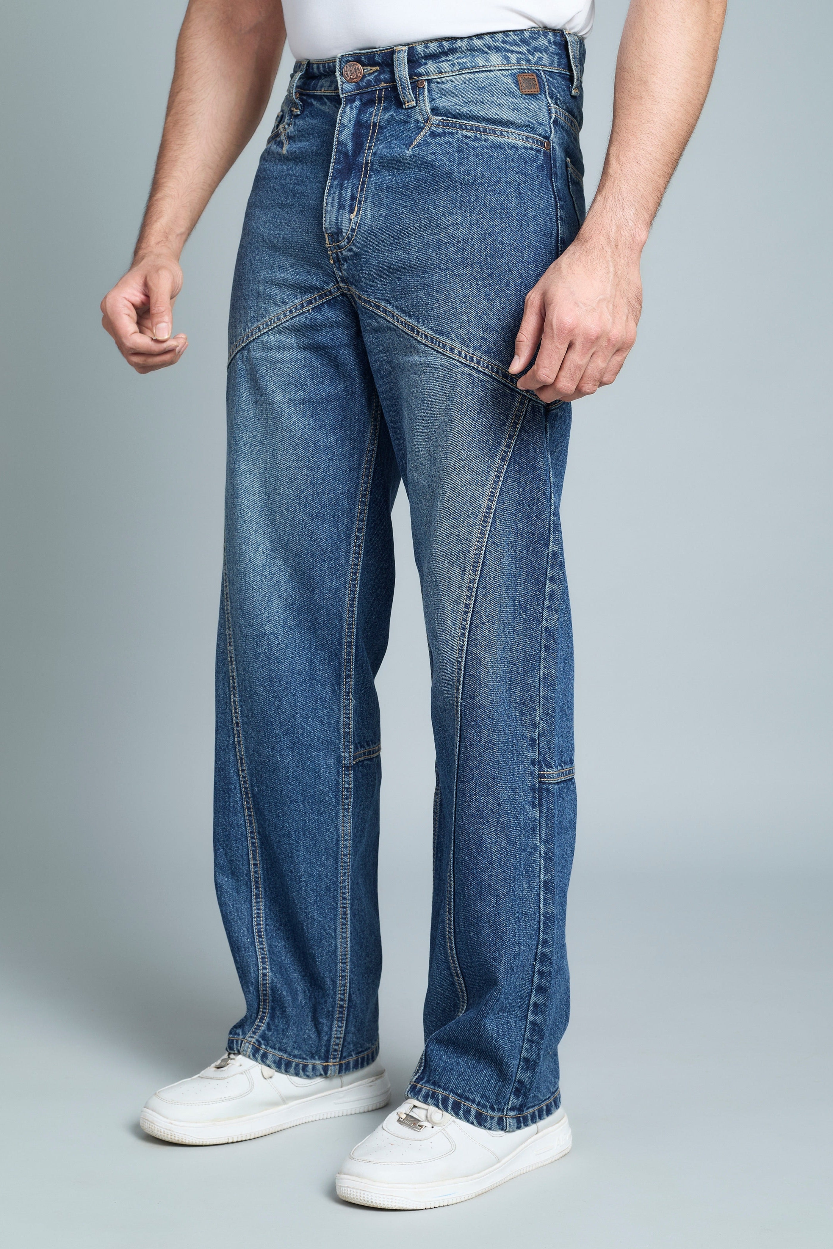 Person wearing blue jeans and white sneakers on a gray background