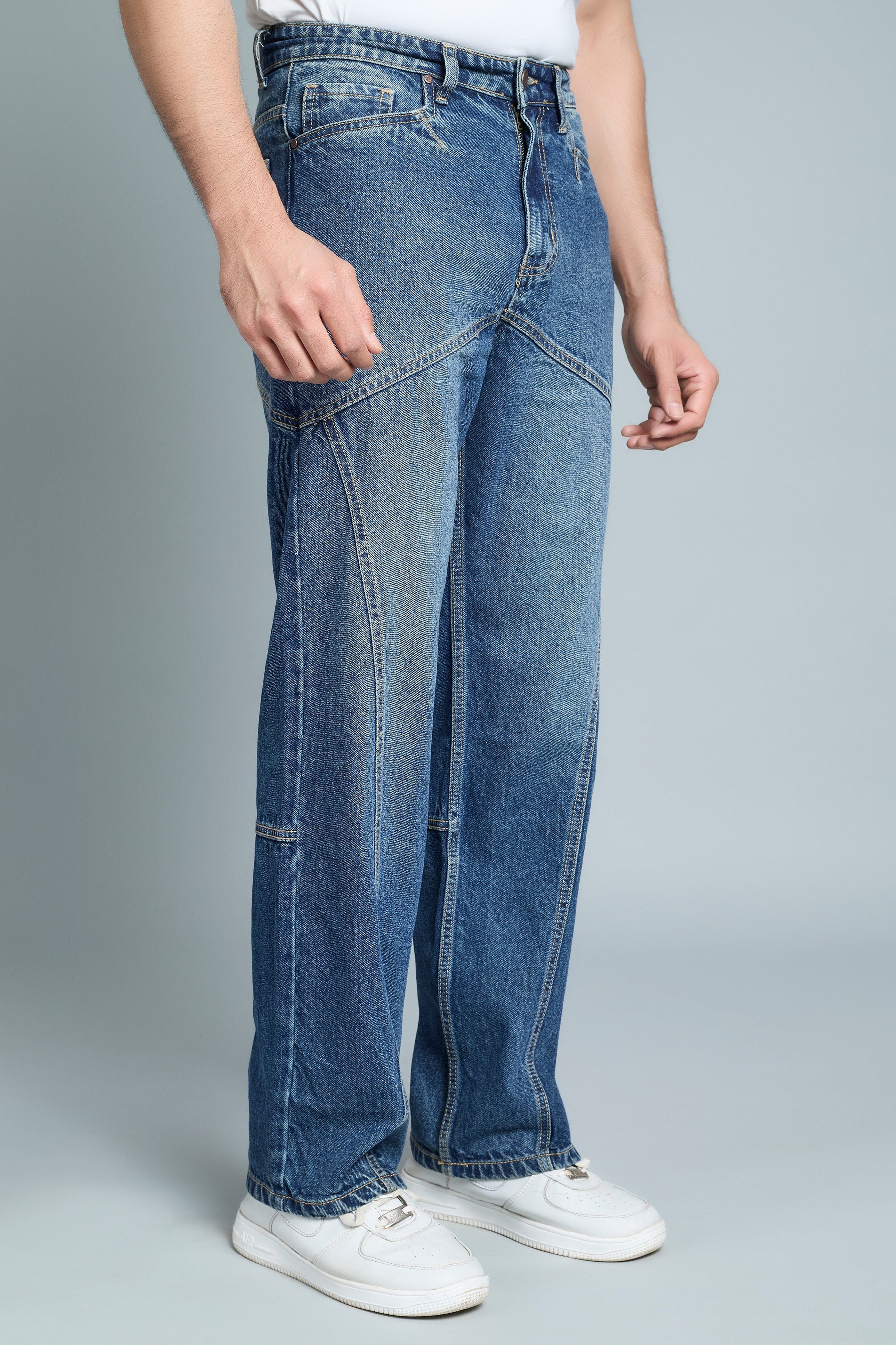 Person wearing blue jeans and white sneakers on a gray background