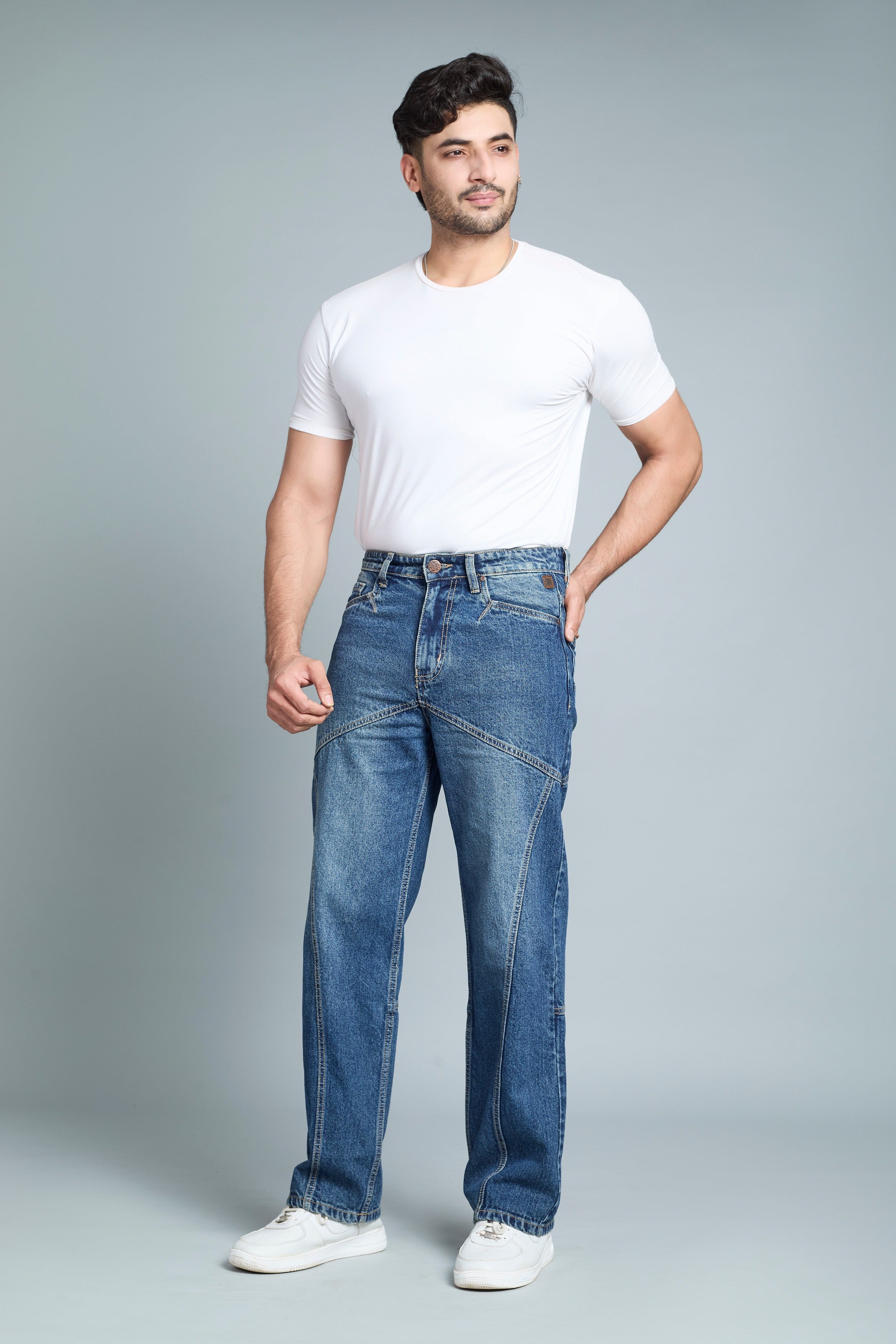 Man wearing a white t-shirt and blue jeans on a gray background