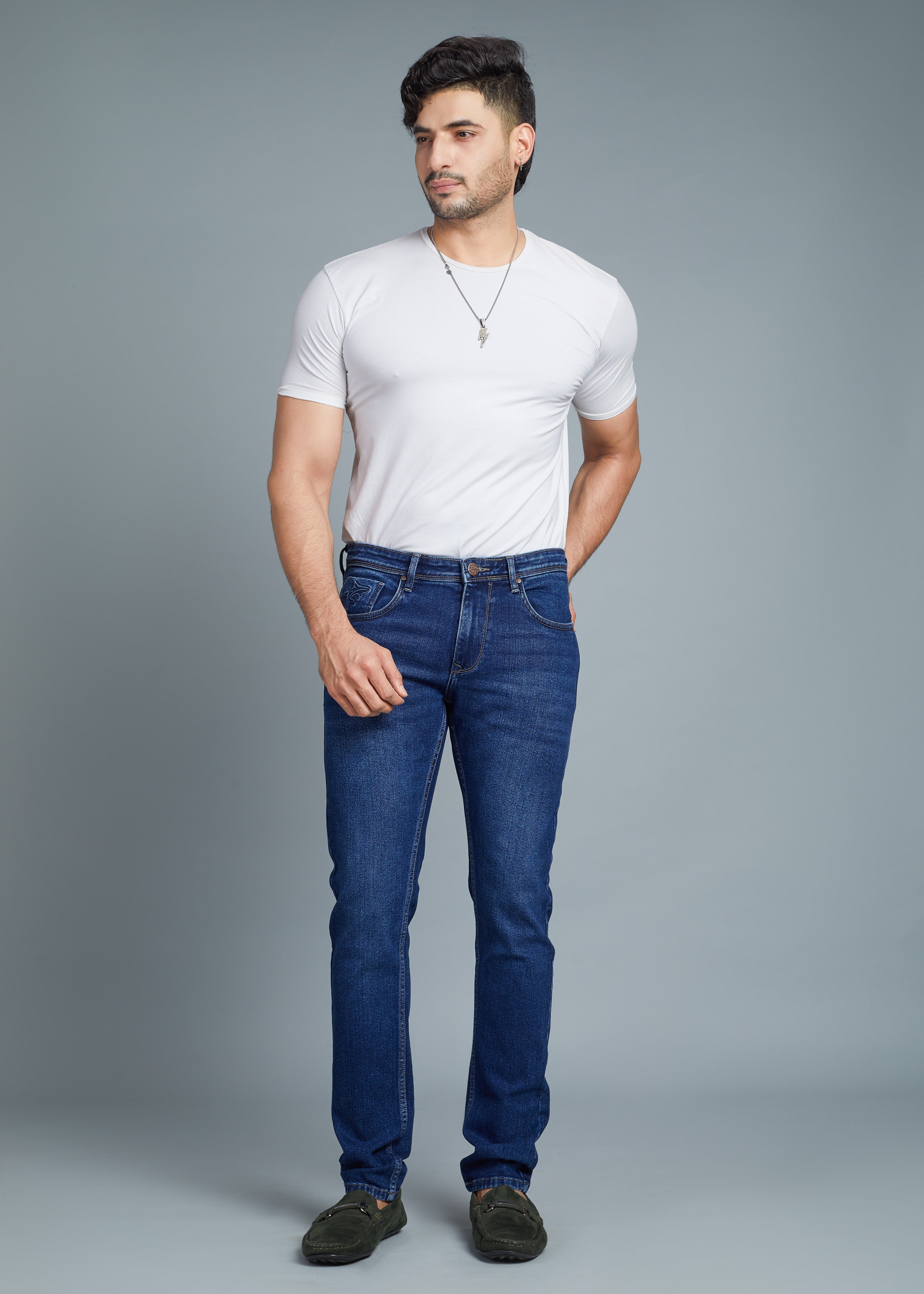 Man wearing a white t-shirt and blue jeans against a gray background