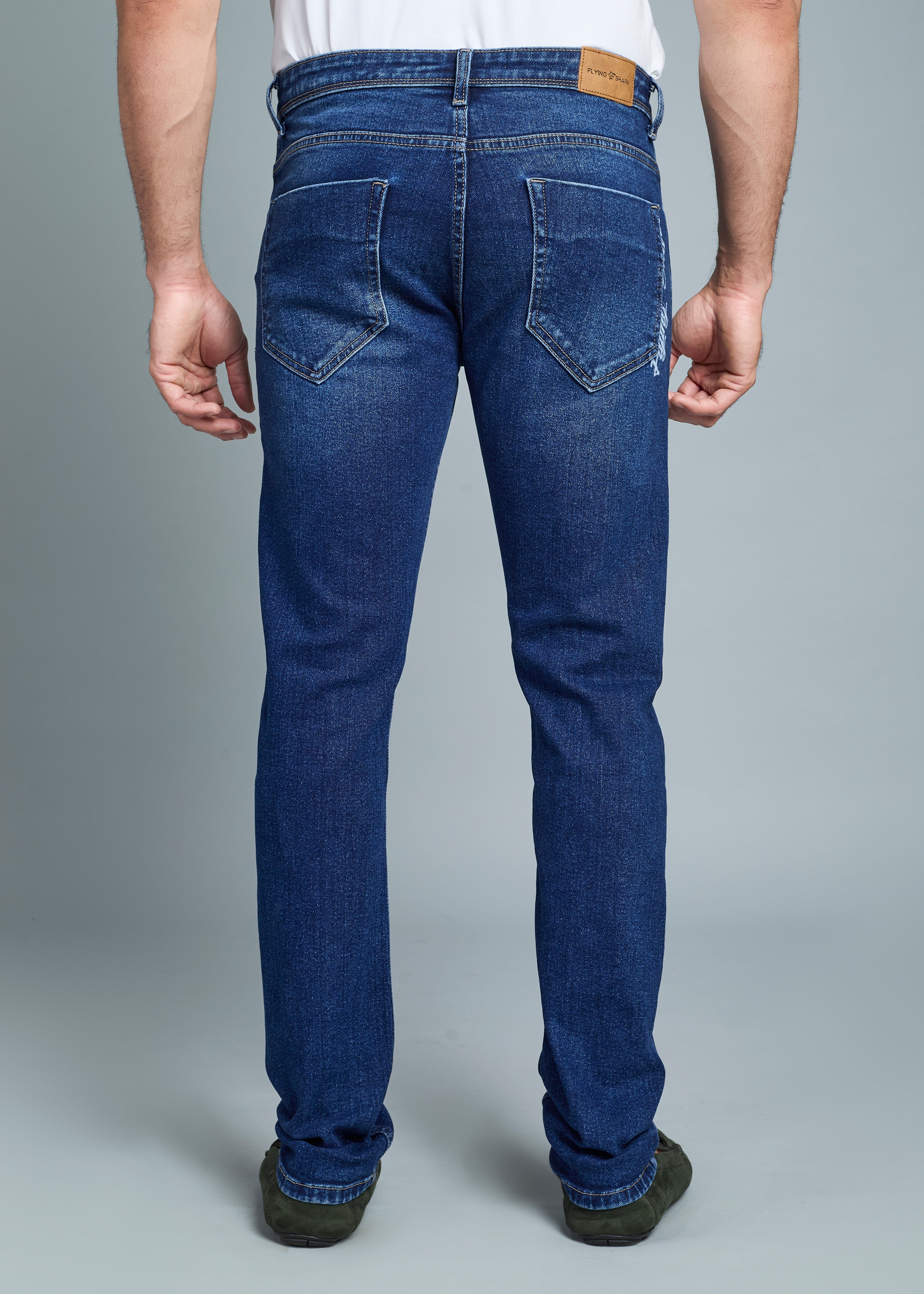 Blue jeans worn by a person on a gray background