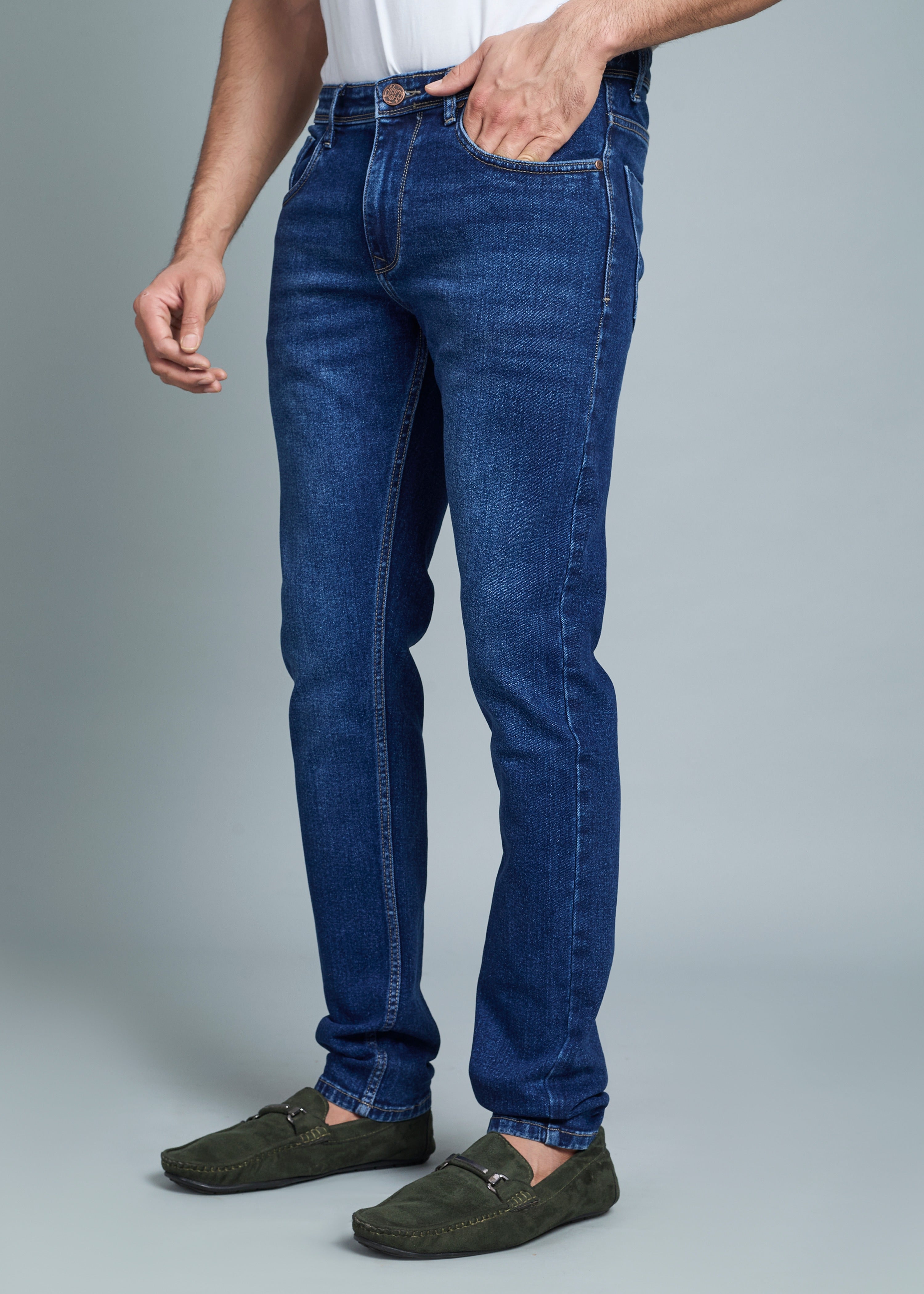 Person wearing blue jeans and green shoes on a gray background