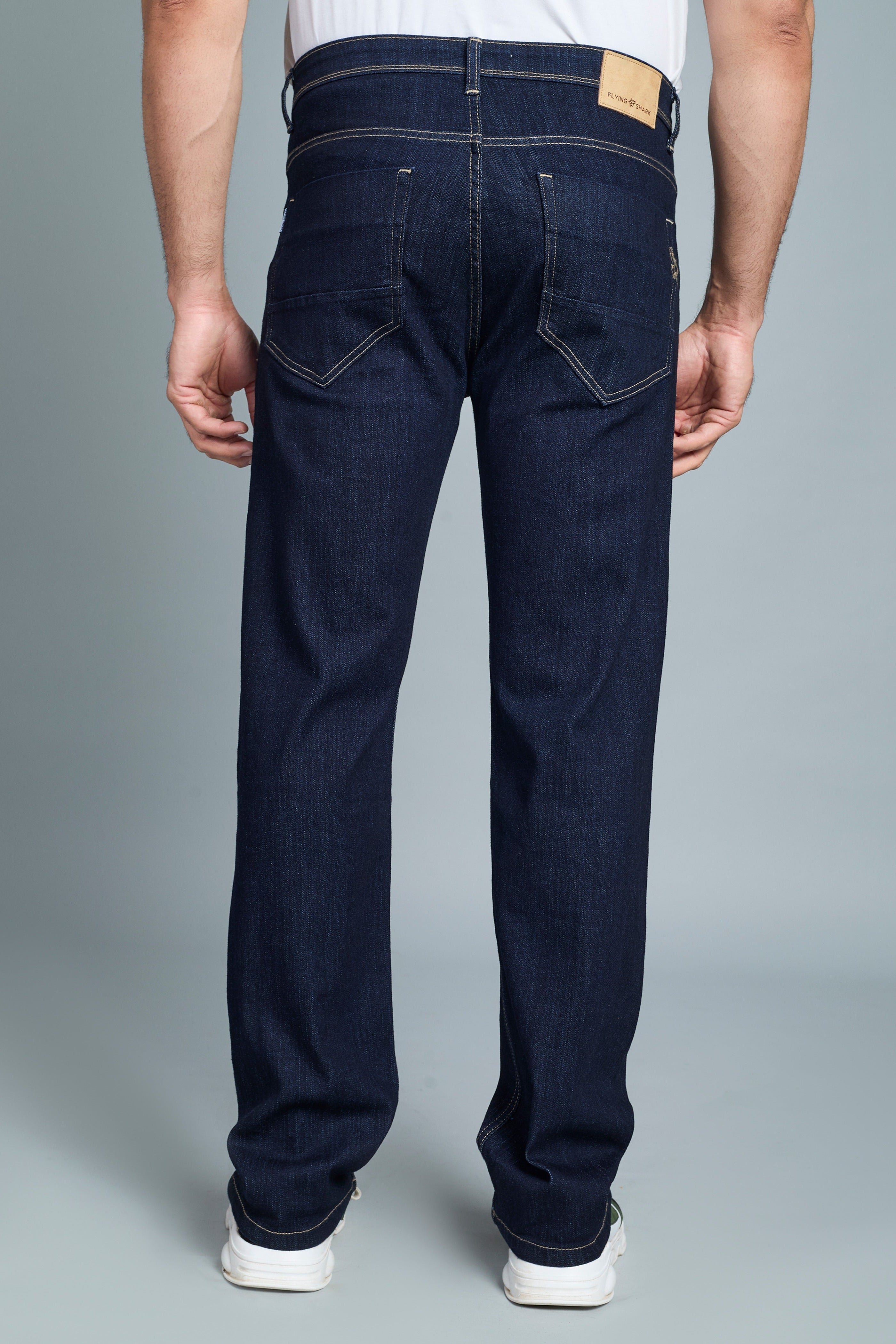 Dark blue jeans worn by a person on a gray background