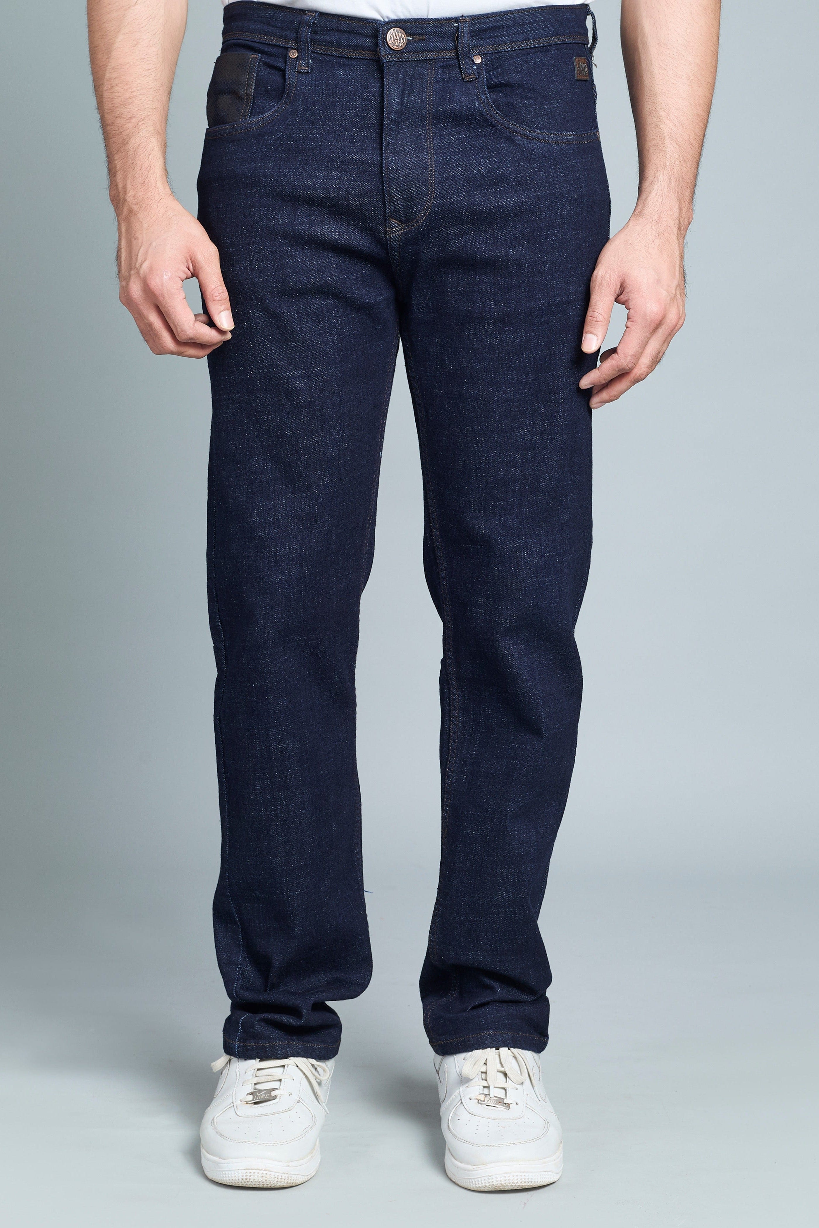 Person wearing dark blue jeans and white sneakers on a gray background