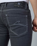 Close-up of dark blue jeans with brand label on a plain background