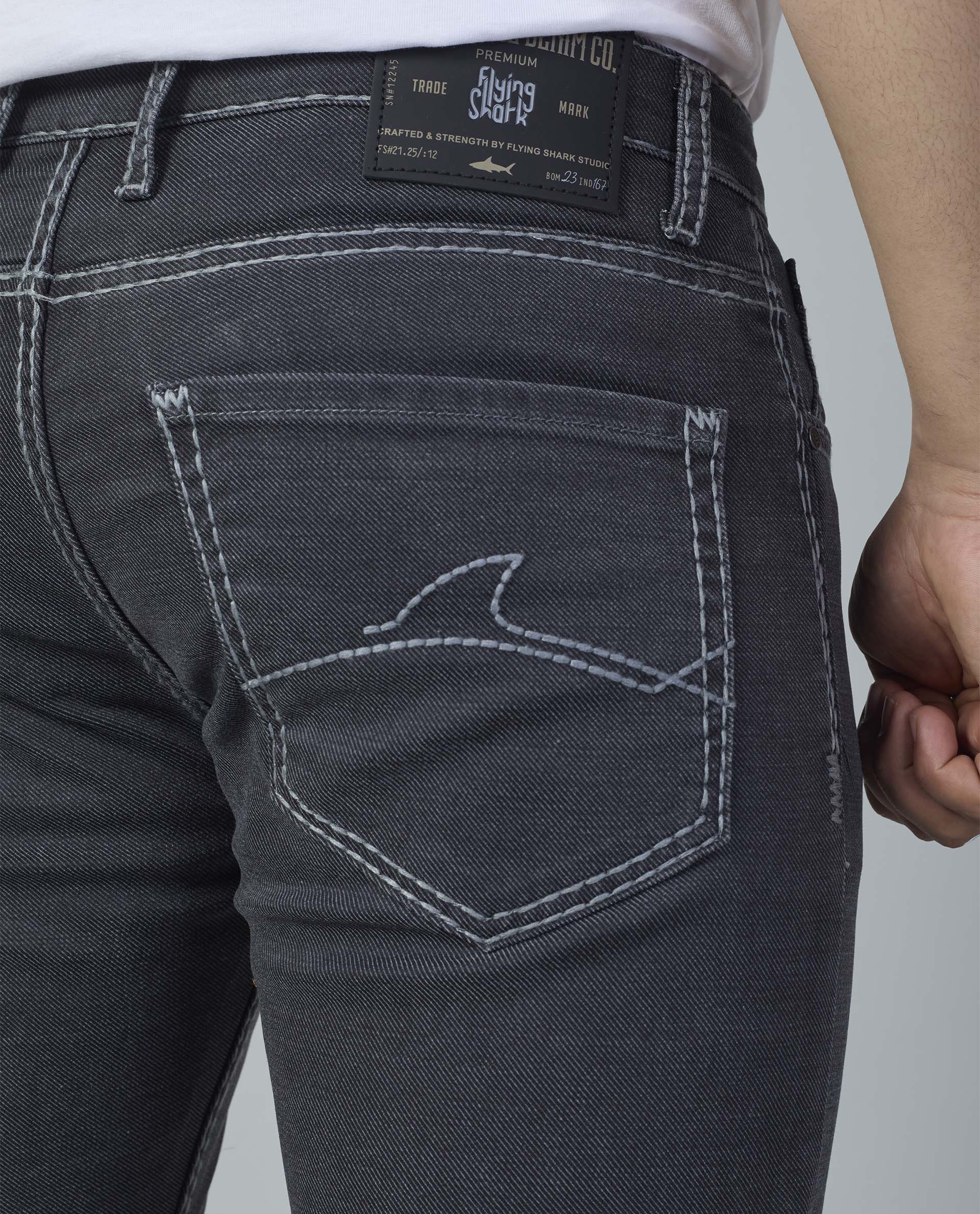 Close-up of dark blue jeans with brand label on a plain background