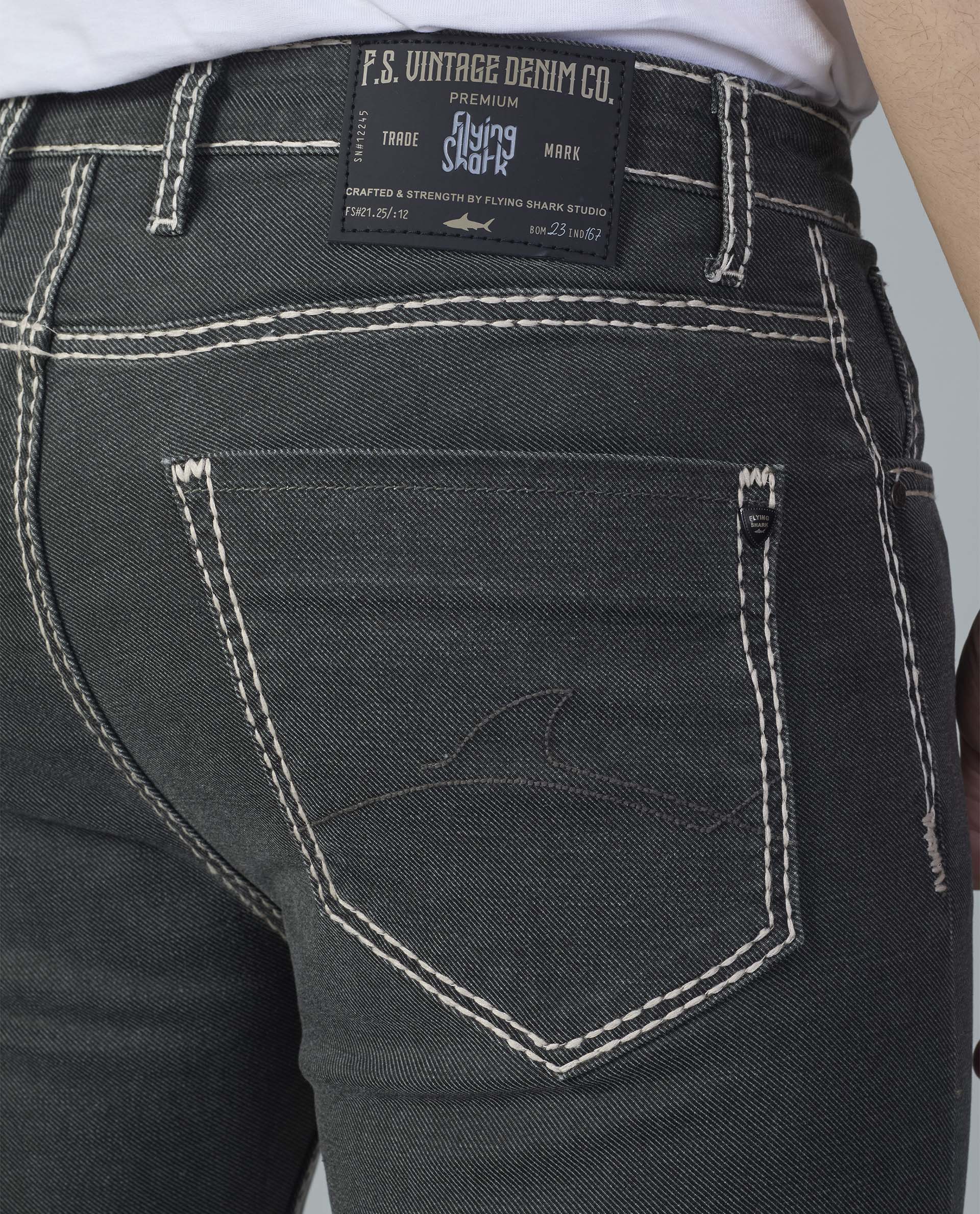Close-up of black jeans with a visible brand label on a gray background
