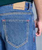 Close-up of blue jeans with a brand label on the back pocket against a neutral background